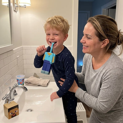 A boy laughing while he brushes his teeth with the Steve Minecraft toothbrush, his mom beside him
