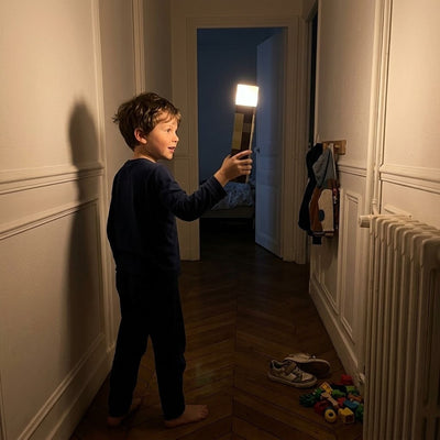 Boy carrying the glowing Pixel Torch down a dark hallway